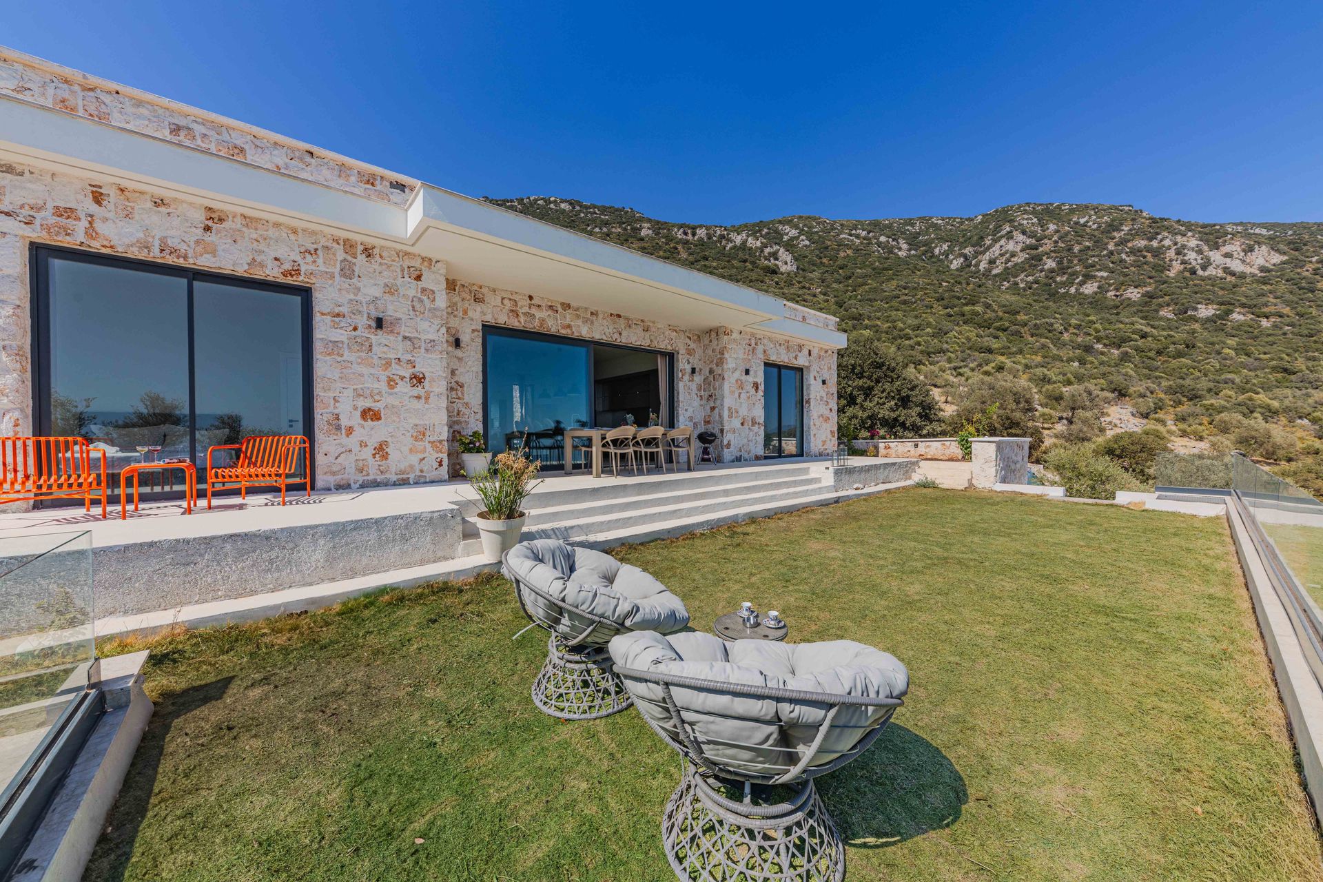 Villa de piedra con muro cortina de cristal y vistas a la montaña